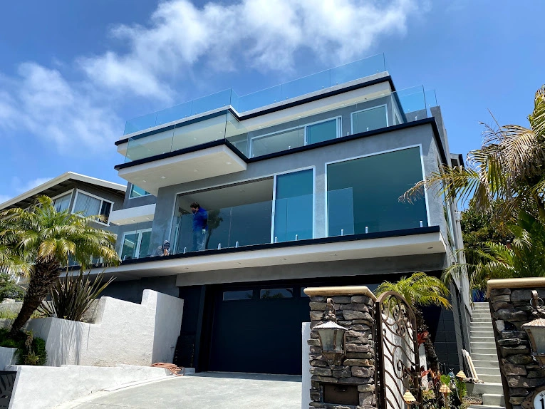 Modern glass-fronted house with palm trees.