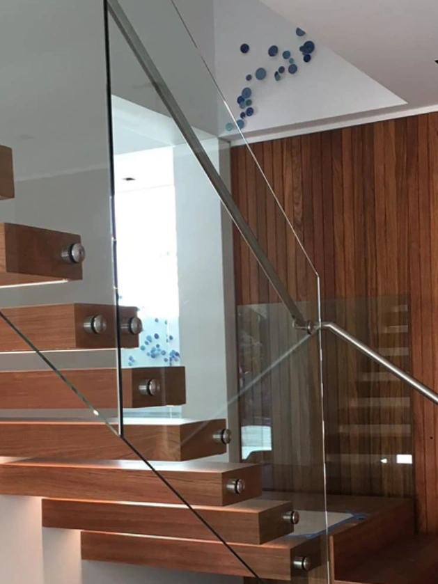 Modern wooden staircase with glass railing.