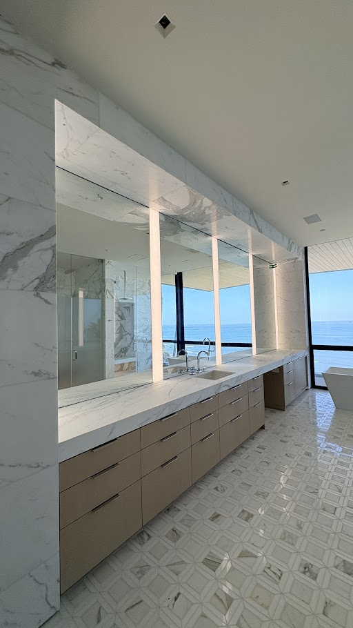 Modern bathroom with ocean view and mirrors.
